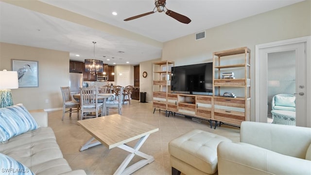 tiled living room featuring ceiling fan with notable chandelier