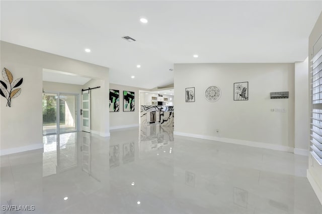 unfurnished room with vaulted ceiling and a barn door