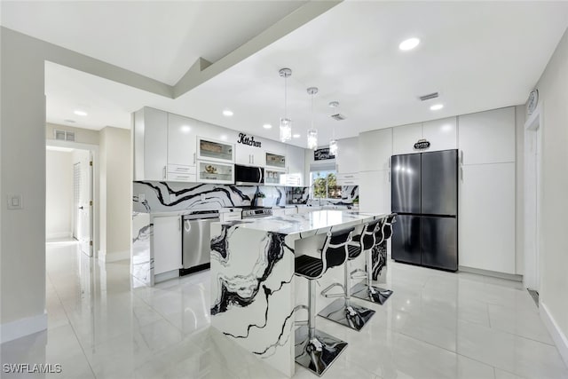 kitchen featuring white cabinetry, a center island, hanging light fixtures, appliances with stainless steel finishes, and backsplash