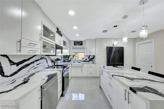 kitchen with light tile patterned flooring, decorative light fixtures, white cabinets, stainless steel appliances, and light stone countertops