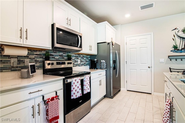 kitchen with decorative backsplash, white cabinets, and appliances with stainless steel finishes