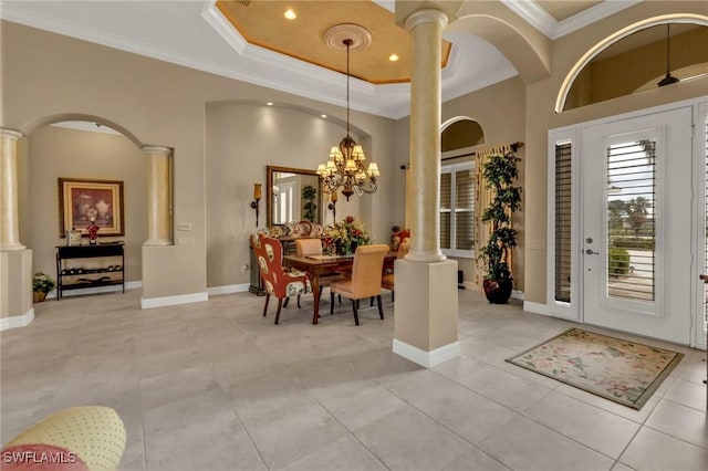 foyer entrance with a notable chandelier, a towering ceiling, ornamental molding, and decorative columns