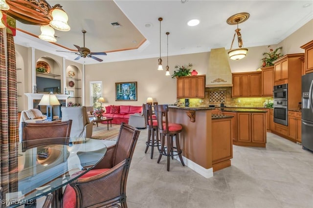 kitchen with hanging light fixtures, a center island, stainless steel appliances, crown molding, and custom range hood