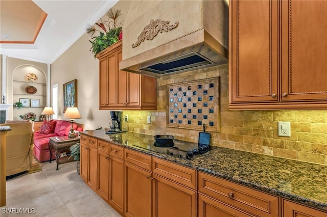 kitchen featuring crown molding, black electric stovetop, custom range hood, and dark stone countertops