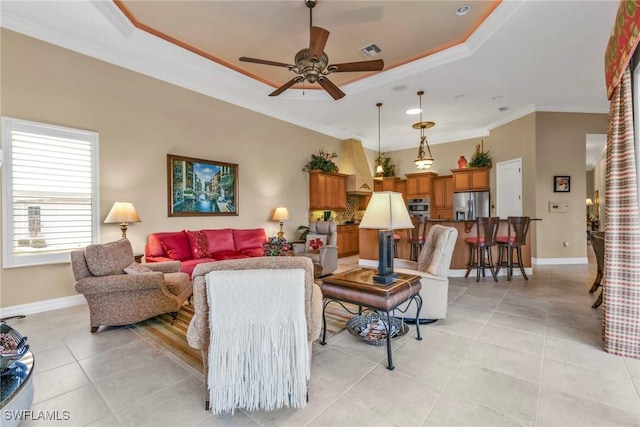 tiled living room with crown molding, ceiling fan, and a tray ceiling