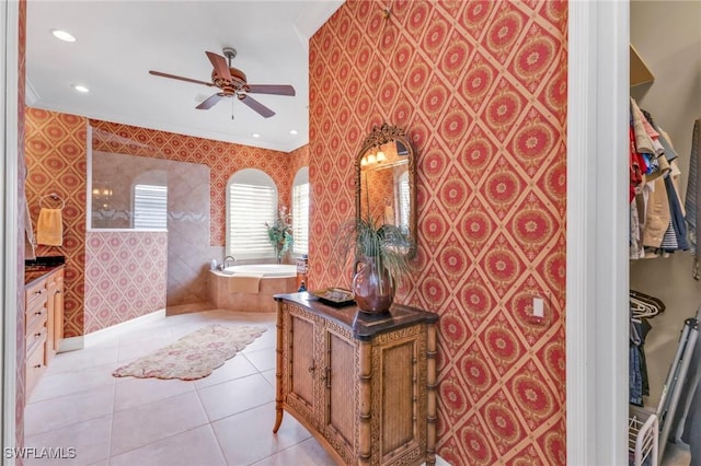 bathroom featuring ornamental molding, vanity, tiled tub, ceiling fan, and tile patterned flooring