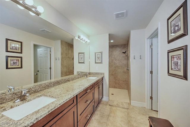 bathroom featuring vanity, tile patterned flooring, and a tile shower