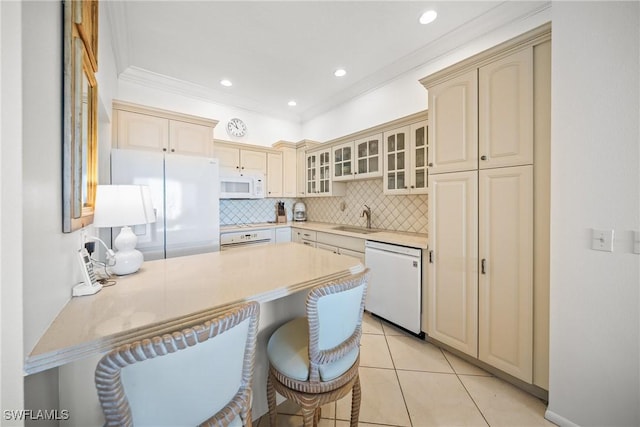 kitchen with backsplash, cream cabinets, glass insert cabinets, a sink, and white appliances