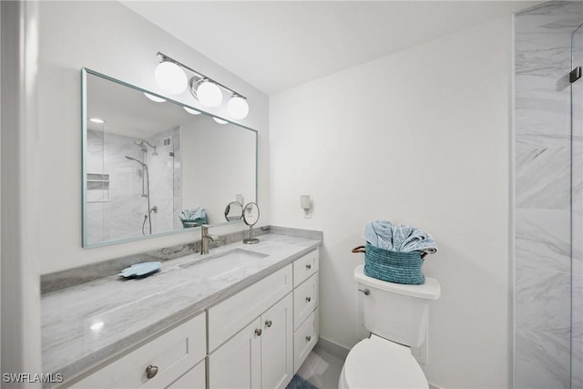 bathroom with vanity, toilet, and tiled shower