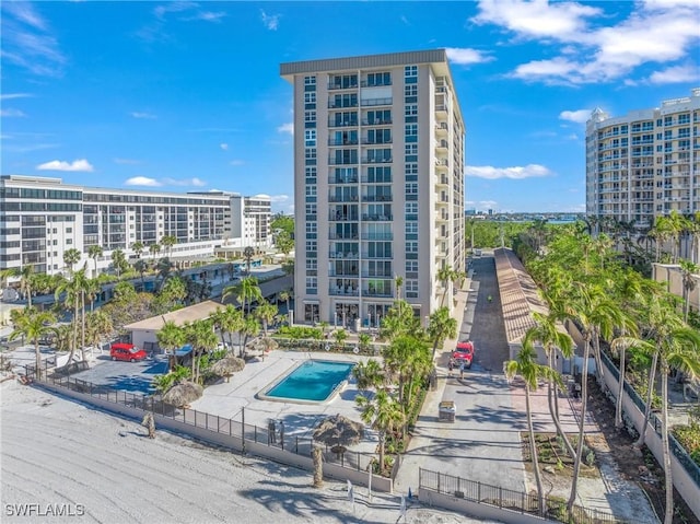 view of property with a community pool, fence, and a city view