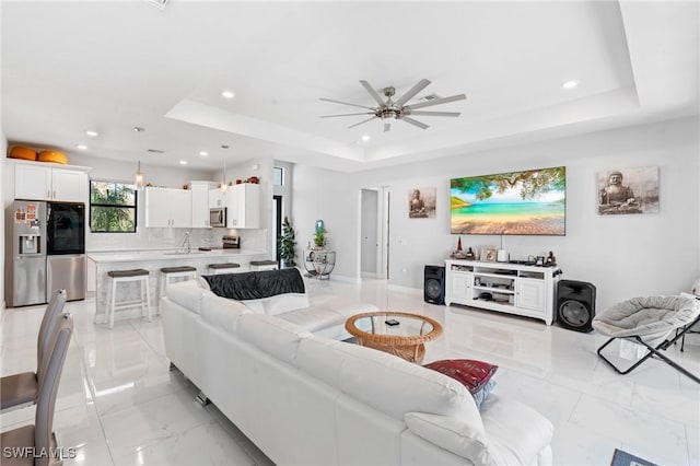 living room featuring a raised ceiling and ceiling fan