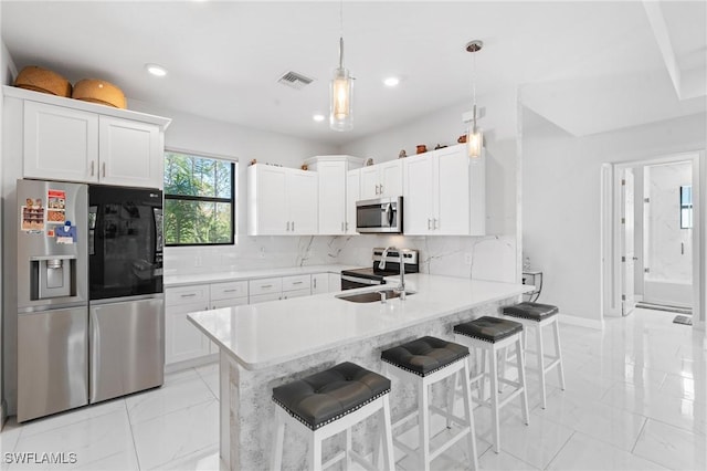 kitchen with pendant lighting, white cabinetry, a kitchen bar, kitchen peninsula, and stainless steel appliances