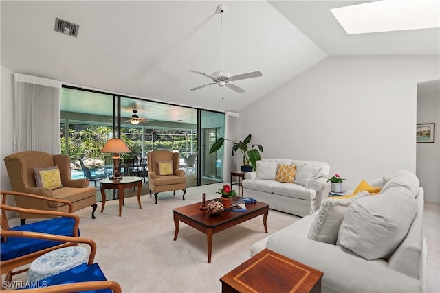 carpeted living room featuring expansive windows, ceiling fan, and vaulted ceiling with skylight