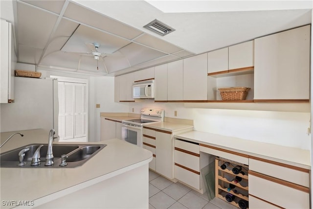 kitchen with sink, white appliances, light tile patterned floors, ceiling fan, and white cabinets