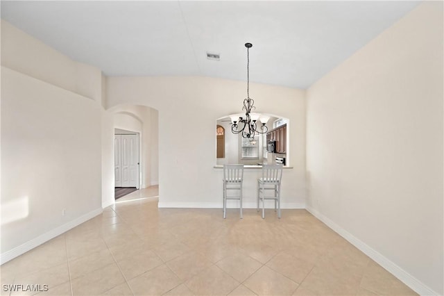 unfurnished dining area featuring light tile patterned floors, vaulted ceiling, and a chandelier