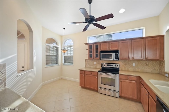 kitchen featuring sink, hanging light fixtures, light tile patterned floors, stainless steel appliances, and backsplash