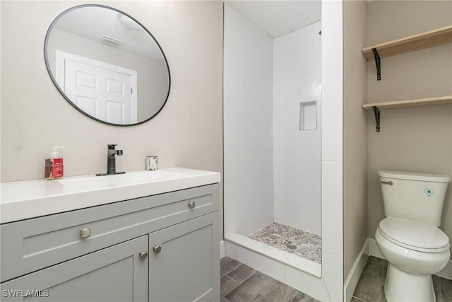 bathroom with vanity, tiled shower, and toilet