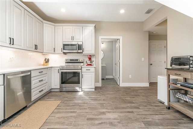 kitchen featuring tasteful backsplash, appliances with stainless steel finishes, light wood-type flooring, and white cabinets