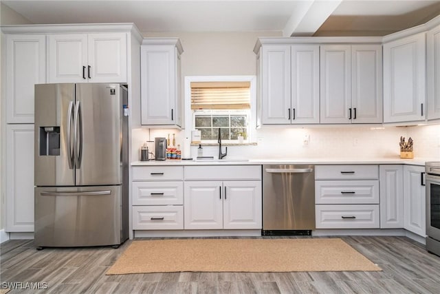 kitchen featuring sink, light wood-type flooring, white cabinets, and appliances with stainless steel finishes