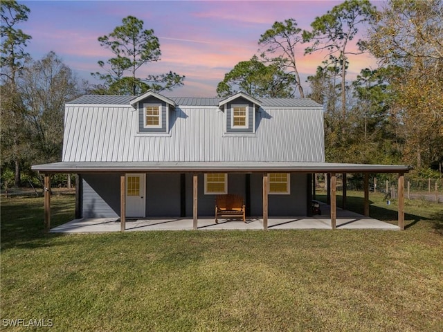 back house at dusk with a patio and a yard