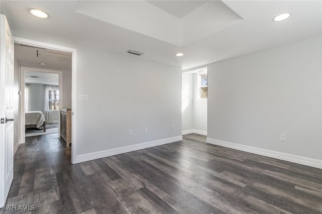 empty room featuring a raised ceiling and dark hardwood / wood-style flooring