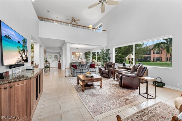 tiled living room with ceiling fan with notable chandelier and decorative columns