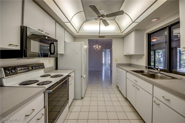 kitchen featuring sink, light tile patterned floors, a tray ceiling, white appliances, and white cabinets