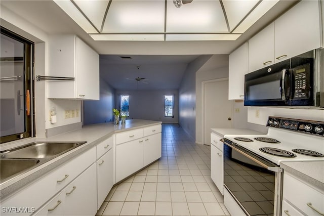 kitchen featuring white range with electric cooktop, kitchen peninsula, light tile patterned floors, and white cabinets