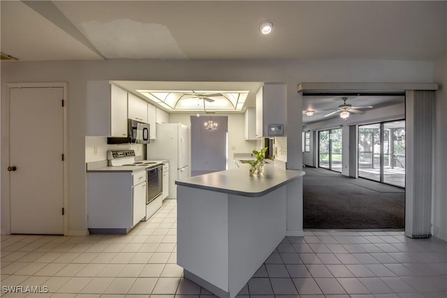 kitchen with white appliances, white cabinetry, a skylight, a raised ceiling, and kitchen peninsula