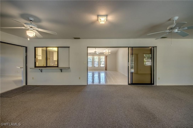 carpeted spare room with ceiling fan with notable chandelier