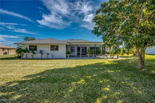 rear view of house featuring a sunroom and a lawn