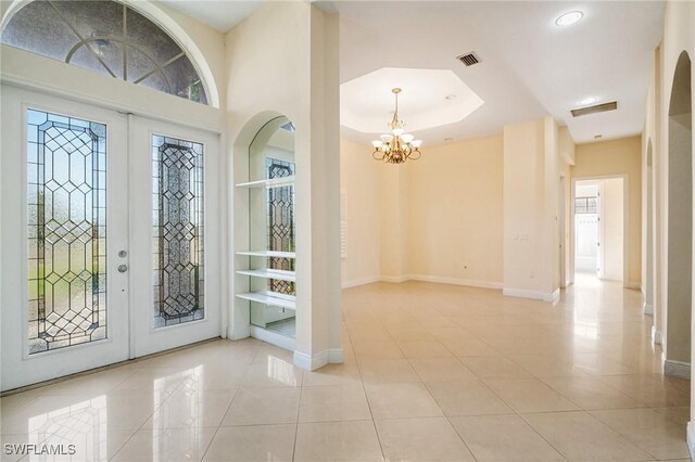 foyer featuring light tile patterned floors, a notable chandelier, and french doors