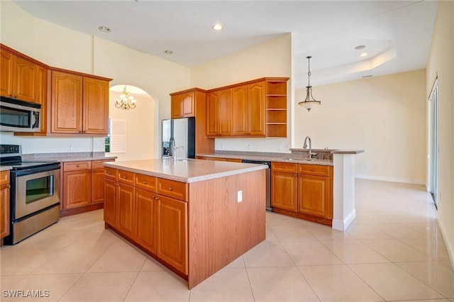 kitchen featuring sink, light tile patterned floors, appliances with stainless steel finishes, an island with sink, and decorative light fixtures