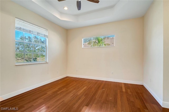 spare room featuring dark wood-type flooring, ceiling fan, and a tray ceiling