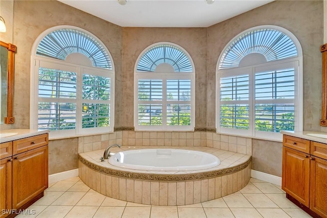 bathroom with a relaxing tiled tub, tile patterned floors, vanity, and a wealth of natural light