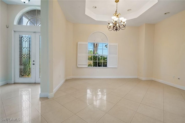 foyer entrance featuring a raised ceiling, a wealth of natural light, and light tile patterned floors