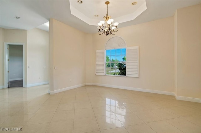 tiled spare room with an inviting chandelier and a raised ceiling