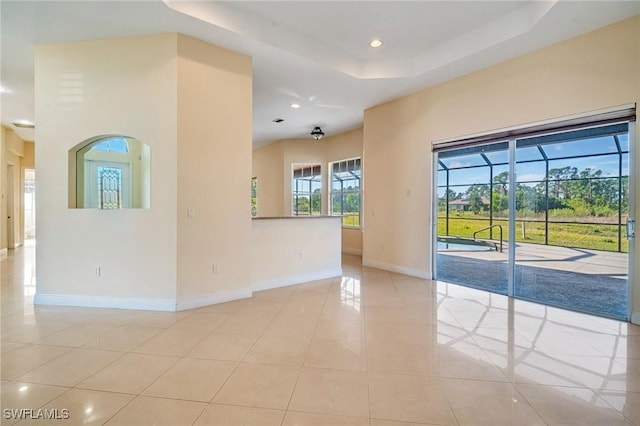 spare room with light tile patterned flooring, a towering ceiling, and a raised ceiling