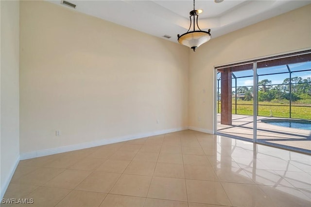 unfurnished room with light tile patterned floors and a tray ceiling