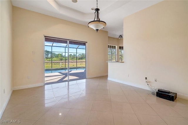 empty room with a raised ceiling and light tile patterned floors