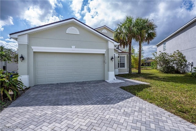 view of front facade featuring a garage, decorative driveway, a front lawn, and stucco siding