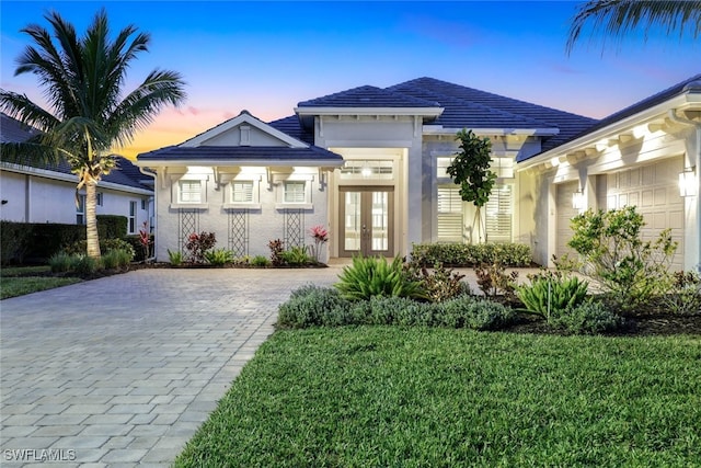 view of front facade with a garage, a yard, and french doors