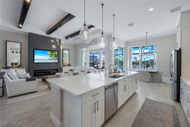 kitchen featuring sink, white cabinetry, decorative light fixtures, appliances with stainless steel finishes, and an island with sink