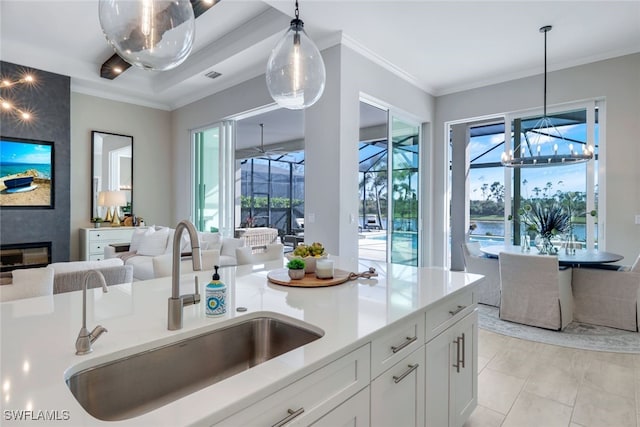 kitchen with white cabinetry, sink, pendant lighting, and ornamental molding