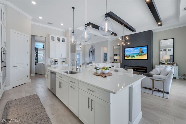 kitchen featuring sink, dishwasher, white cabinetry, hanging light fixtures, and a center island with sink