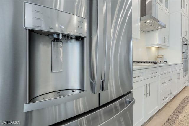 kitchen with white cabinetry, light tile patterned floors, wall chimney exhaust hood, and appliances with stainless steel finishes