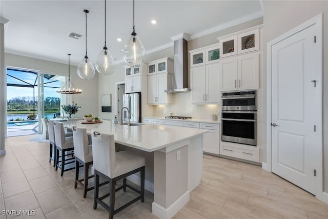 kitchen featuring pendant lighting, white cabinetry, a large island, stainless steel appliances, and wall chimney range hood