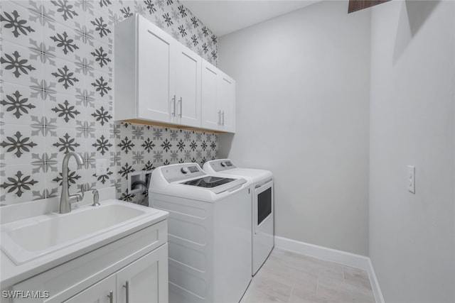 clothes washing area featuring sink, washer and clothes dryer, and cabinets