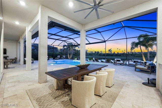 patio terrace at dusk featuring a water view, a lanai, and ceiling fan