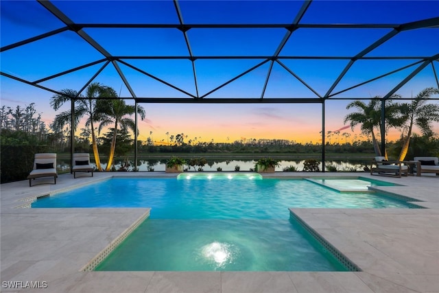 pool at dusk featuring a jacuzzi, a patio area, a water view, and glass enclosure